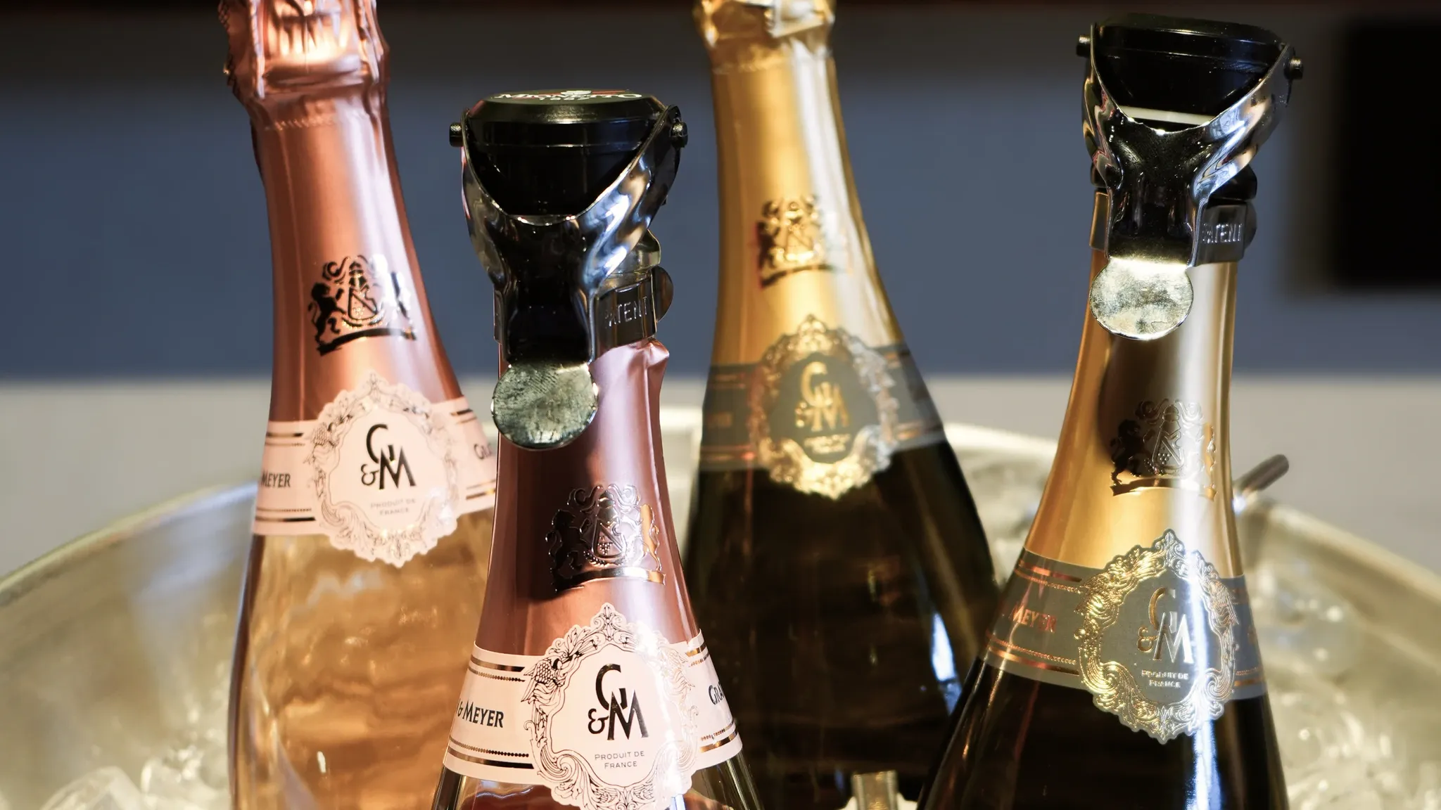 Vier Rosé- und Weißwein-Schaumweinflaschen stehen gekühlt im Eis.