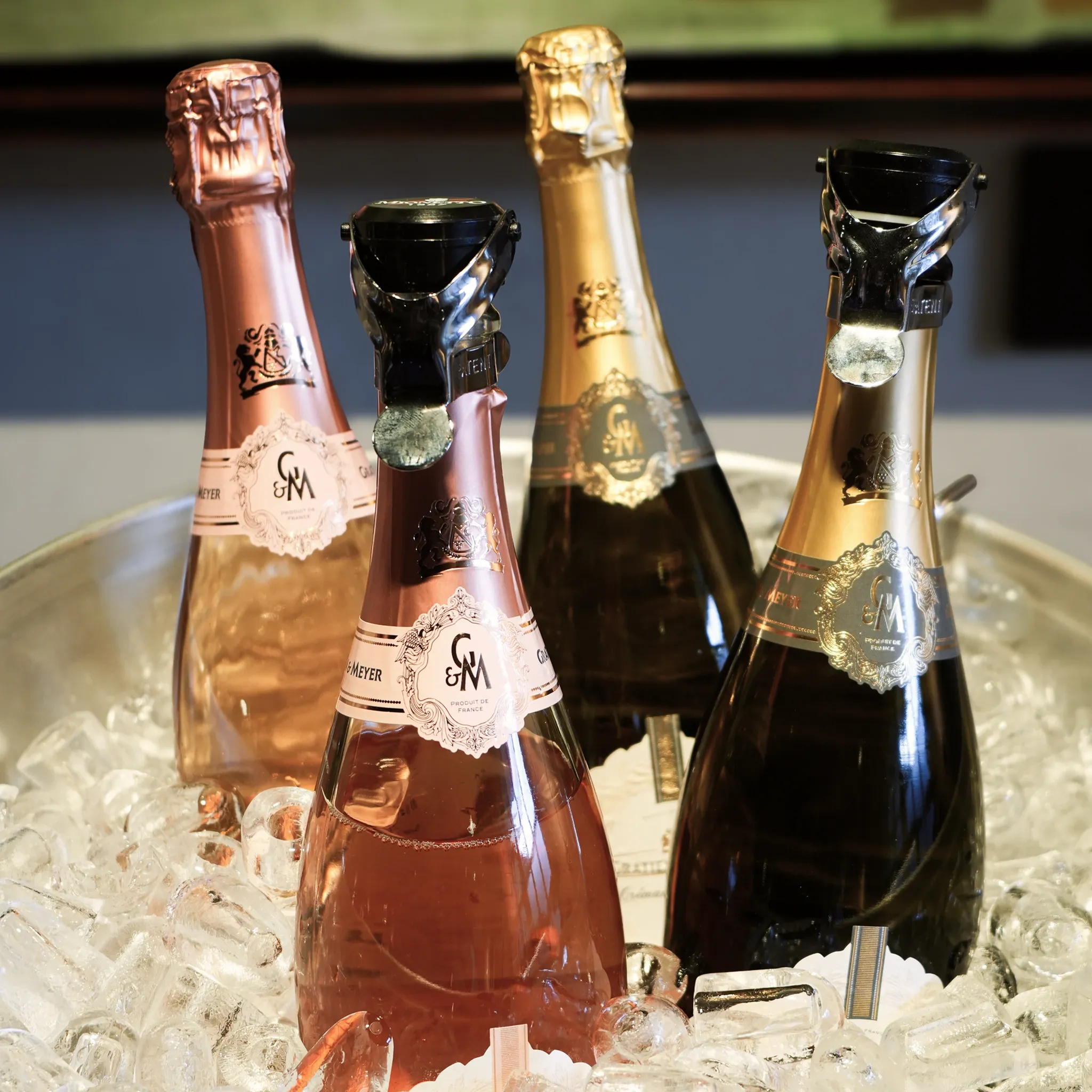 Vier Rosé- und Weißwein-Schaumweinflaschen stehen gekühlt im Eis.