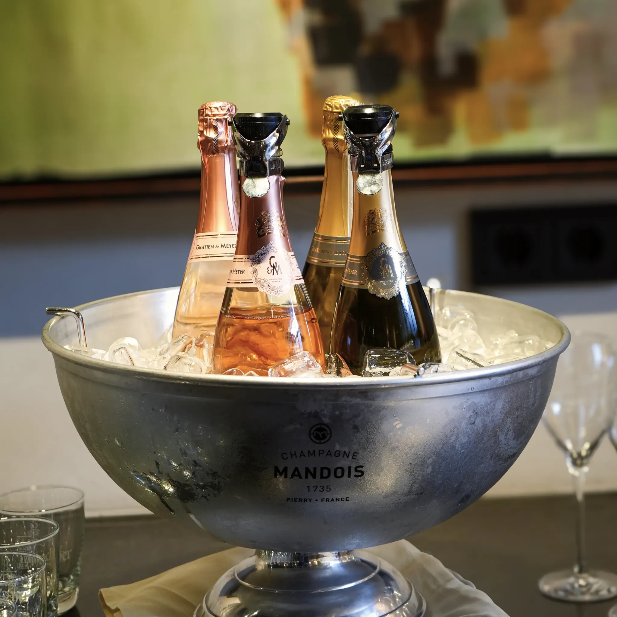 Vier Flaschen Champagner stehen in einem großen Metallkübel auf Eis.