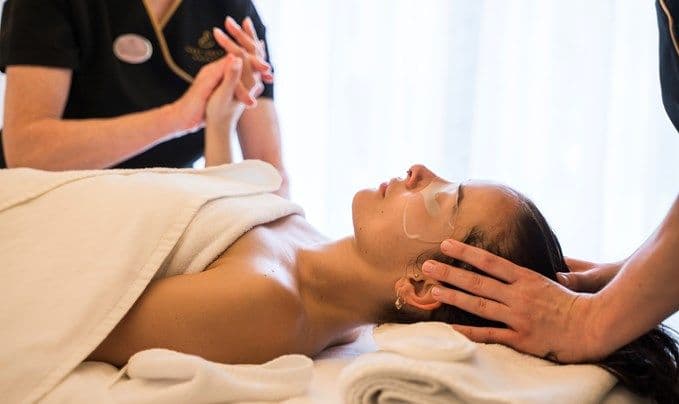 Kosmetikerin gibt einer Frau bei einer Gesichtsbehandlung eine sanfte Kopf- und Gesichtsmassage.