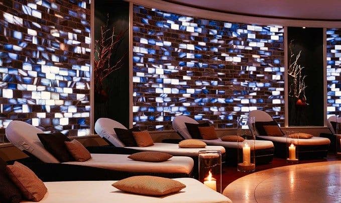 Salzlounge im Engel Obertal mit beleuchteter Wand aus blauem persischem Salzstein und gepolsterten Ruheliegen im warmen Kerzenlicht.