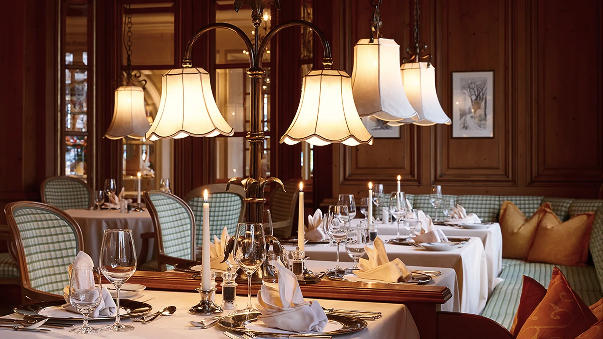 Restaurantsaal mit Holzvertäfelung, Stehlampen und weiß eingedeckten Tischen.