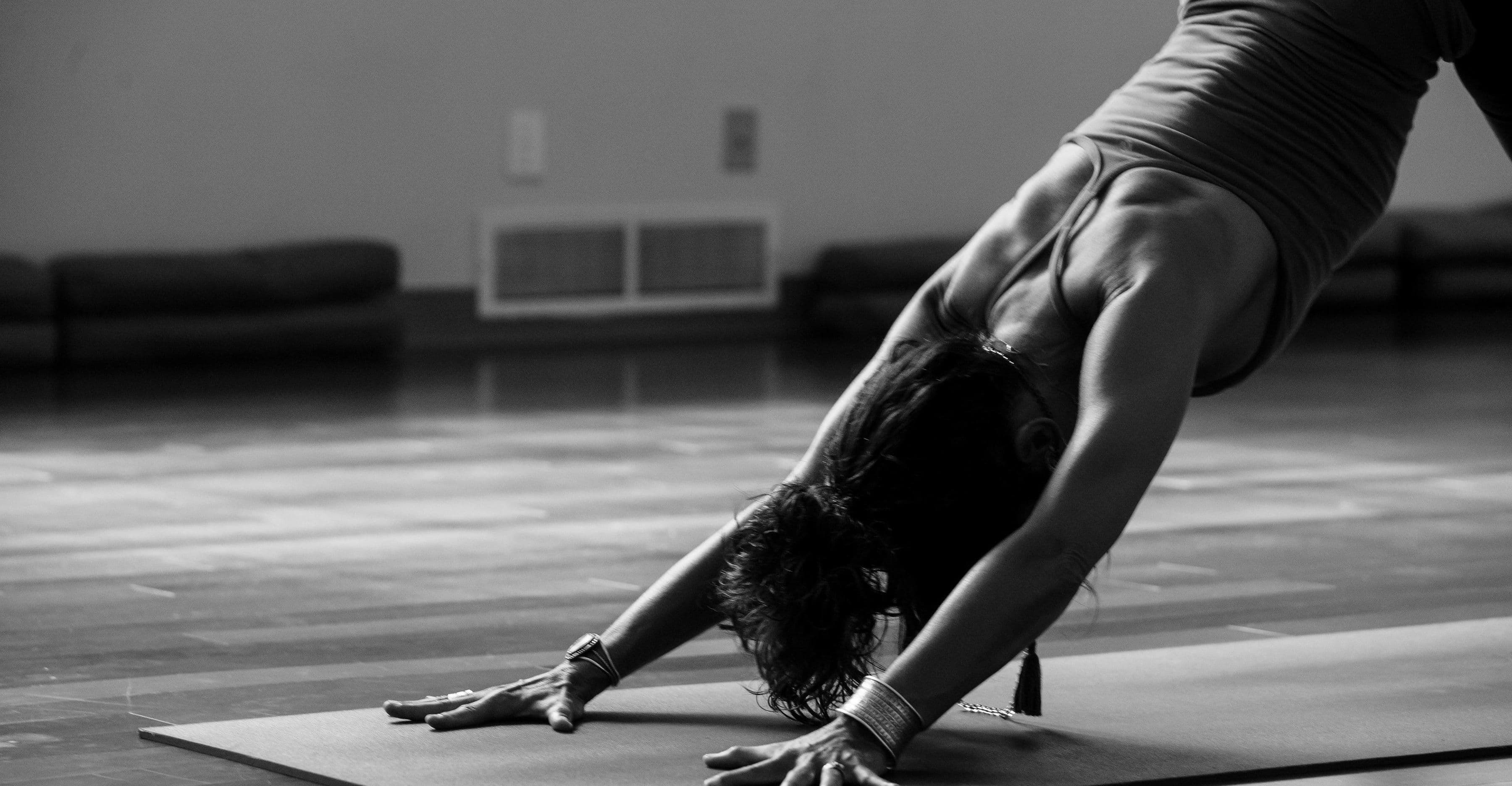 Frau in der Yoga-Position herabschauender Hund auf einer Matte, Schwarz-Weiß-Aufnahme