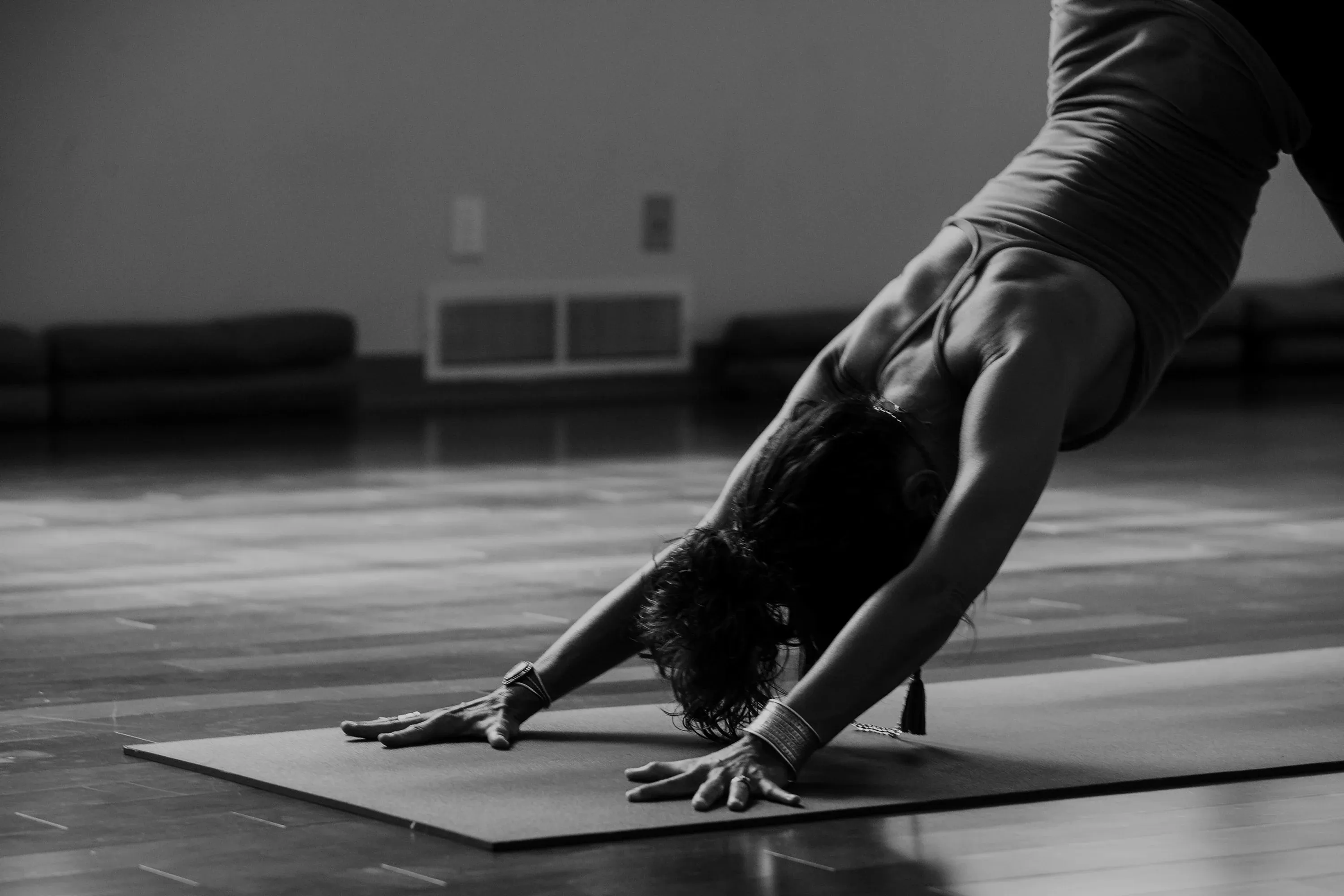 Frau in der Yoga-Position herabschauender Hund auf einer Matte, Schwarz-Weiß-Aufnahme