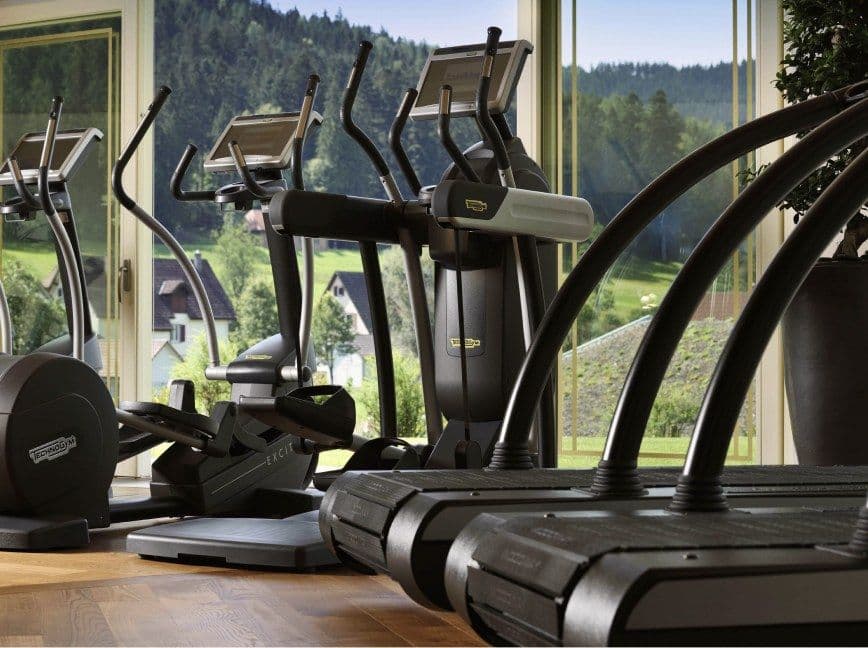 Crosstrainer und Laufbänder im Fitnessbereich vor einer Fensterfront mit Blick in den Schwarzwald
