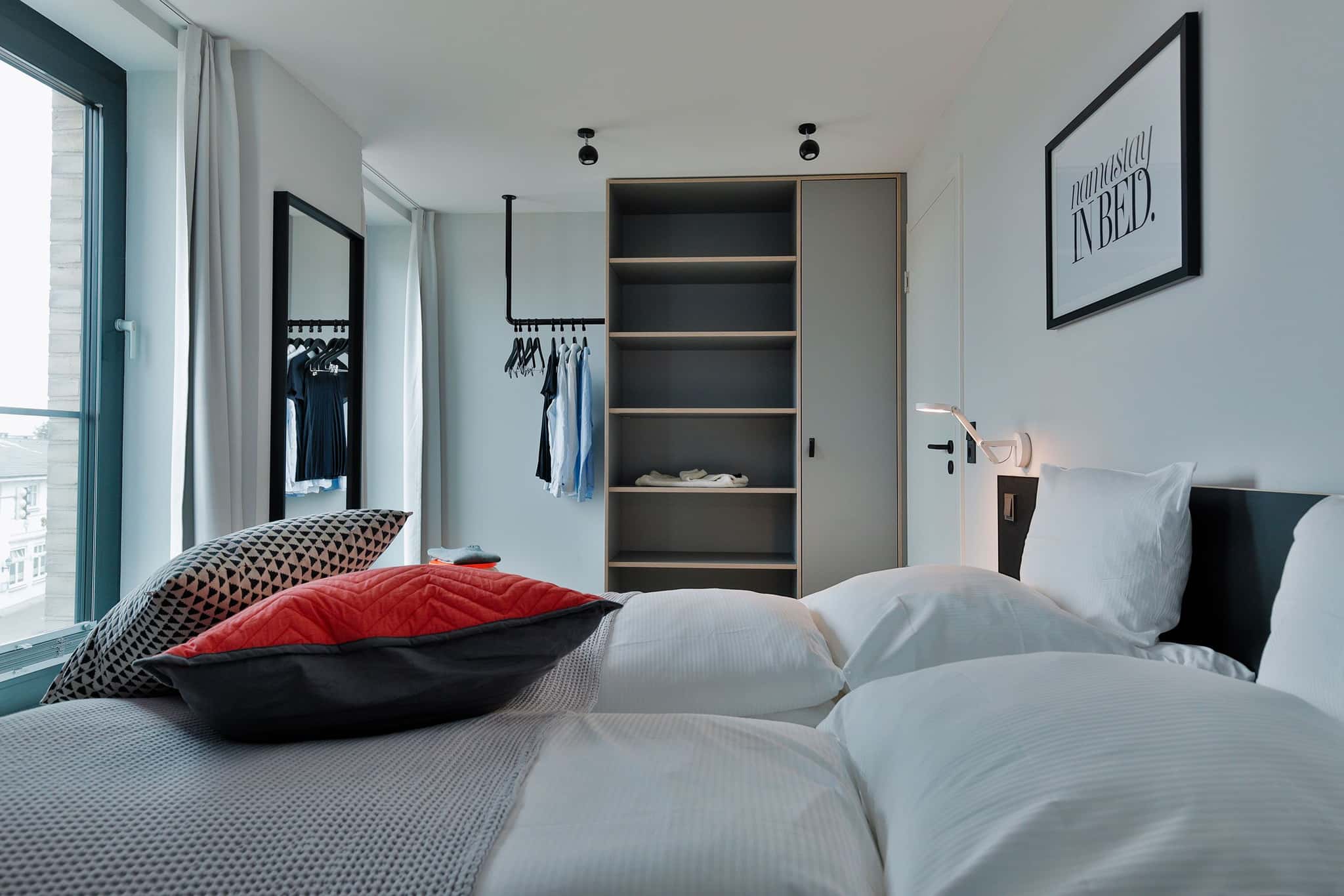 Schlafzimmer mit Doppelbett, Kleiderstange, offenem Regal und Wandbild im Appartement Bett & Bude