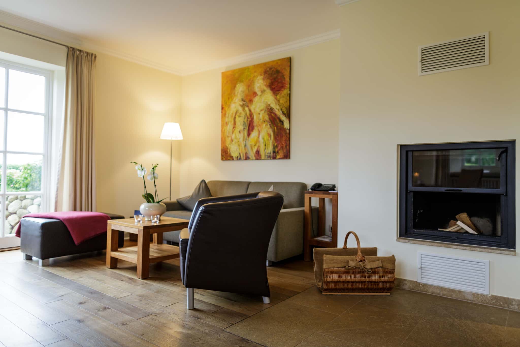 Wohnbereich mit Ledersessel, Sofa, Kamin und Gemälde im Appartement Meerlavendel im Lüüvhoog