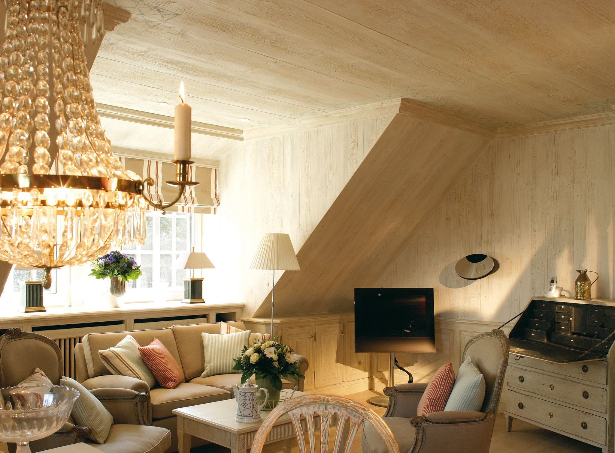 Wohnzimmer mit Sofa, Sesseln, Kronleuchter und Sekretär unter der Dachschräge, Ferienwohnung Tipkenhoog