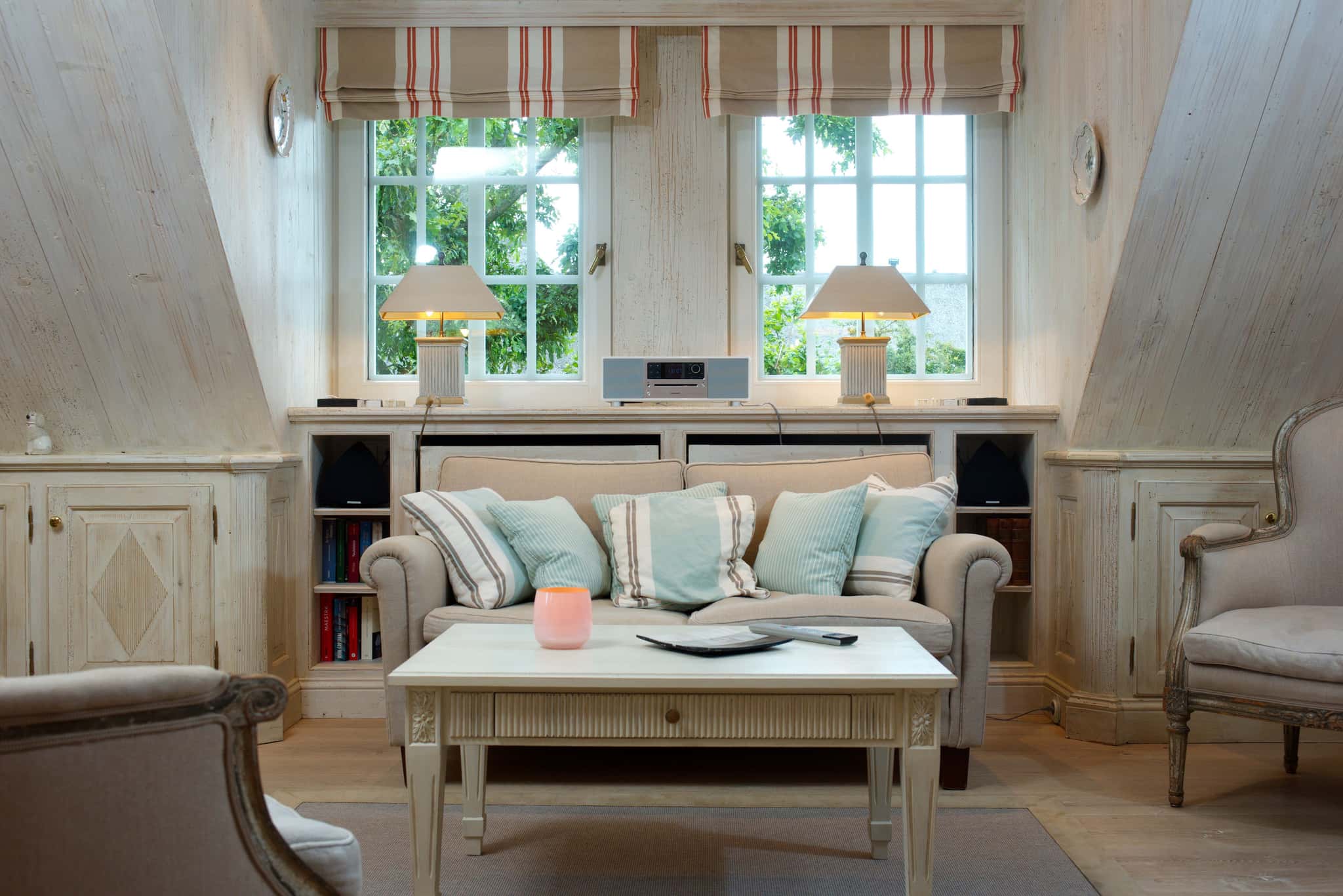Sofa mit Kissen vor Sprossenfenstern, Couchtisch und Sessel in der Ferienwohnung Tipkenhoog